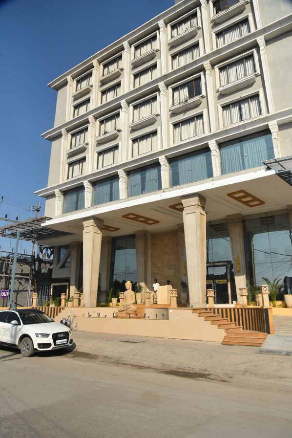 A multi-story hotel with a prominent entrance, large windows, and a white car parked in front.