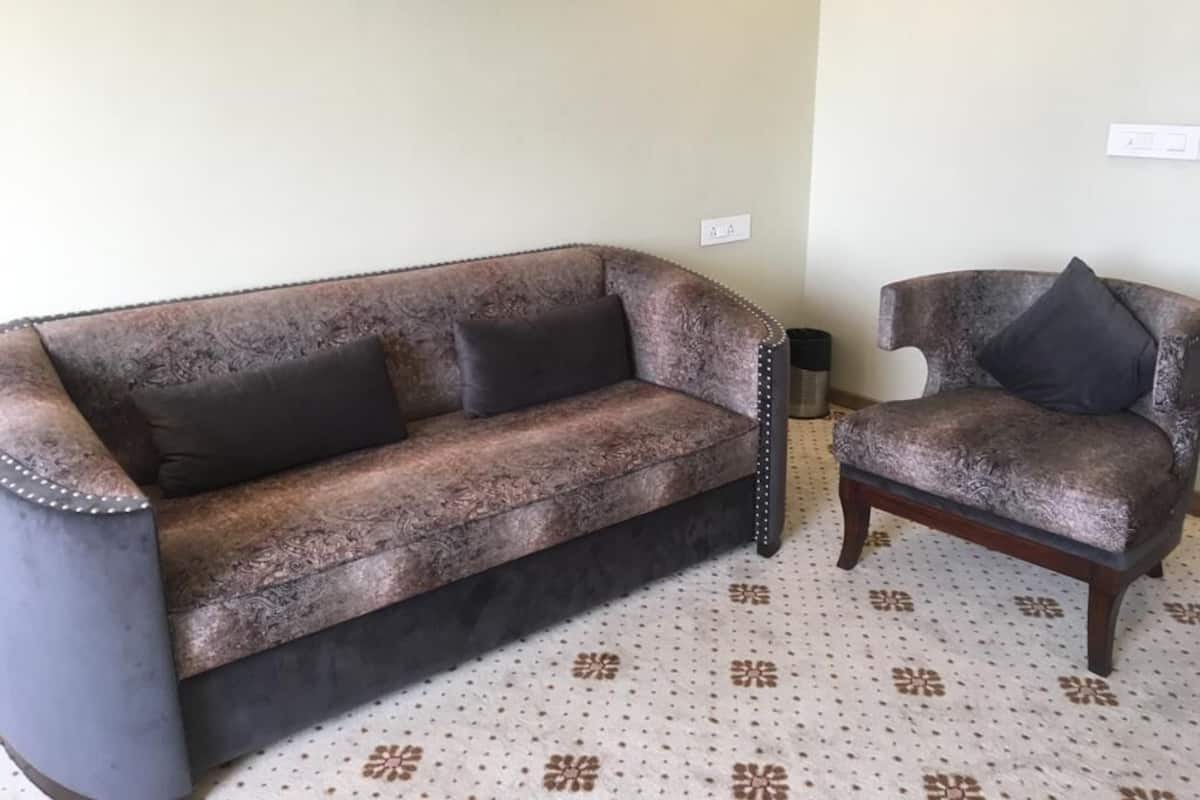 Ein Zimmer mit einem gemusterten Teppich, einem dunkelbraunen Sofa und einem passenden Sessel.