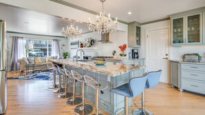 A modern kitchen with a central island, bar stools, a chandelier, and a view of the outside. - Luxurious, Spacious, Great Views, Minutes to Ocean (Aptos)