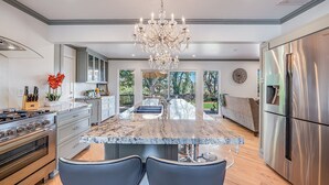 A modern kitchen with a large island, stainless steel appliances, and a chandelier. - Luxurious, Spacious, Great Views, Minutes to Ocean (Aptos)