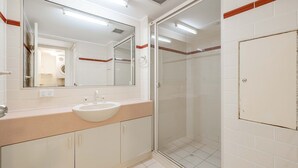A modern bathroom with a large mirror, a sink, and a glass shower enclosure. - Seacrest Unit 4 Moffat Beach QLD (MOFFAT BEACH)