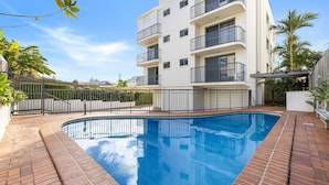 A modern apartment building with a swimming pool, balconies, and a gated entrance. - Seacrest Unit 4 Moffat Beach QLD (MOFFAT BEACH)