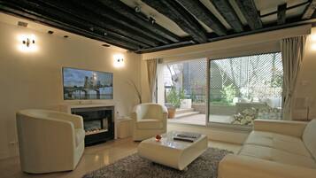 A modern living room with a fireplace, comfortable seating, and a large window offering a view of the outdoors.
