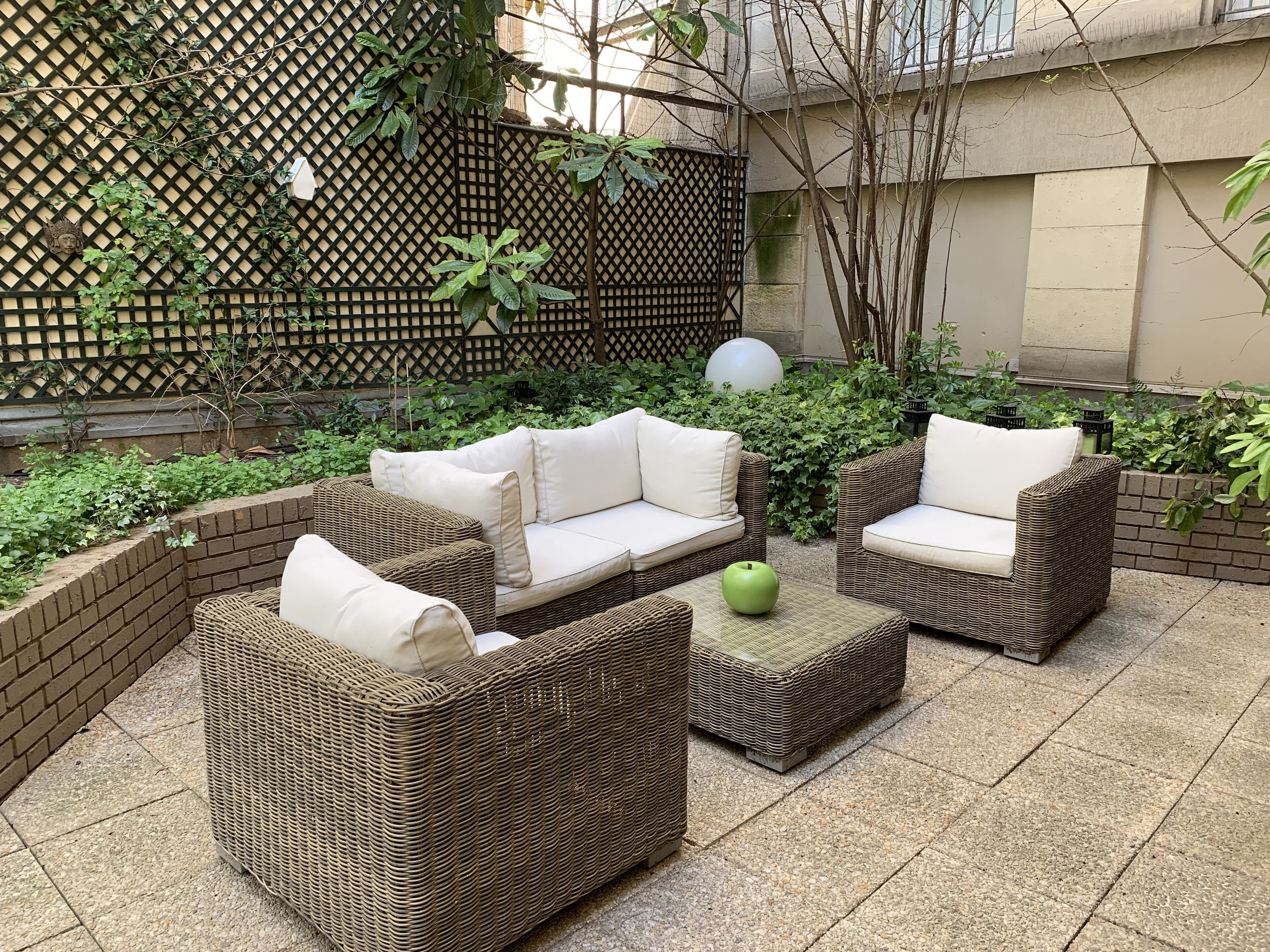 Un espace patio aménagé avec des meubles en osier et une pomme verte posée sur une table.