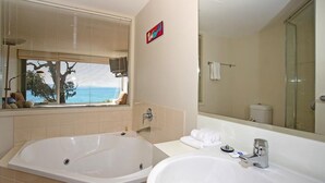 A bathroom with a large bathtub, a sink, and a mirror. - Apartment 7 Kalimna (Lorne)
