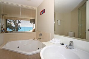 A bathroom with a large bathtub, a sink, and a mirror. - Apartment 7 Kalimna (Lorne)