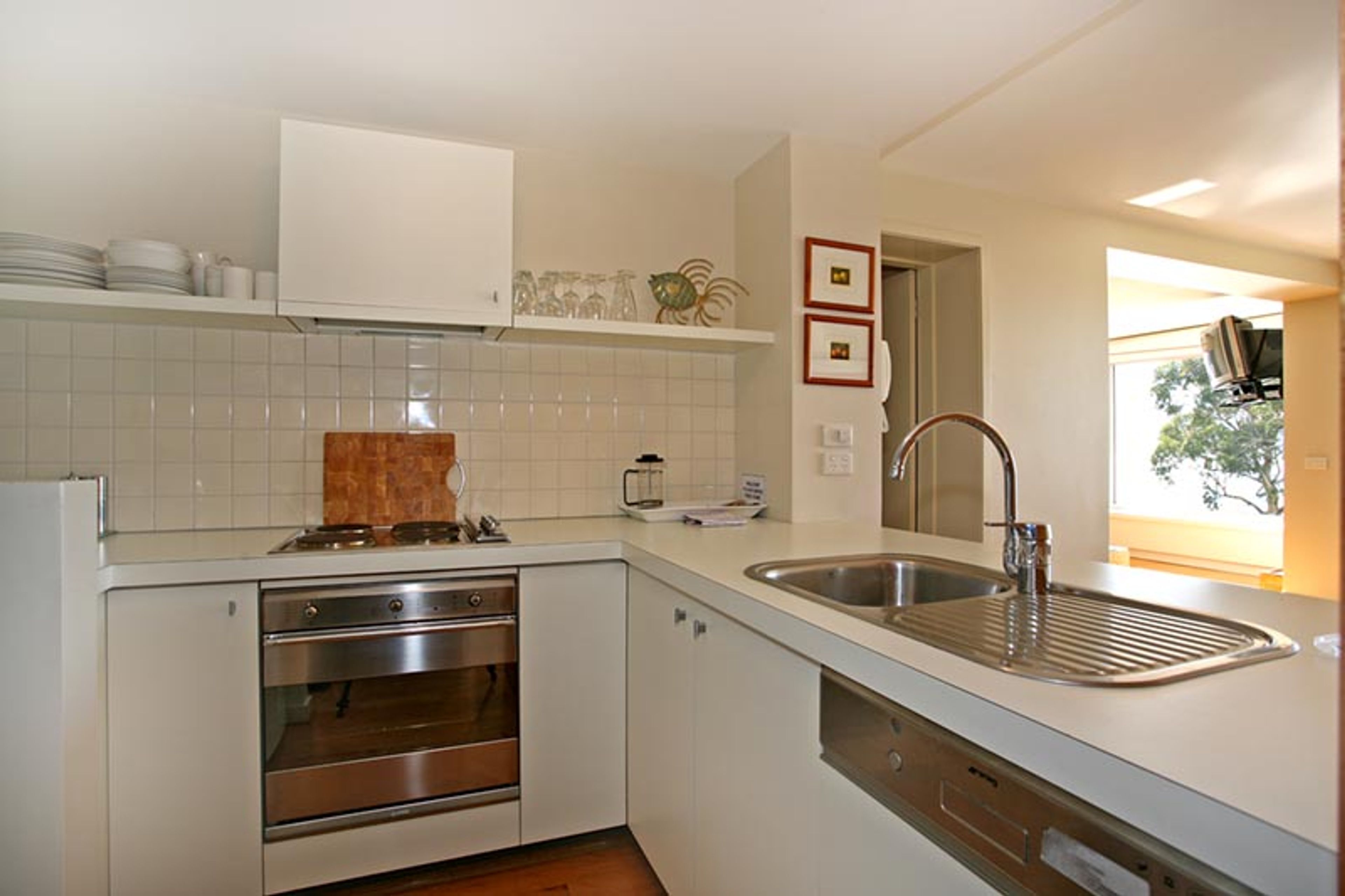 A modern kitchen with white cabinetry, a stainless steel sink, and a built-in oven.