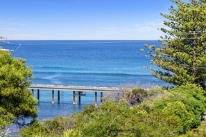 A coastal view with a pier extending into the sea, surrounded by greenery. - Apartment 7 Kalimna (Lorne)