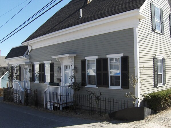 A two-story house with a porch, white siding, and black shutters.