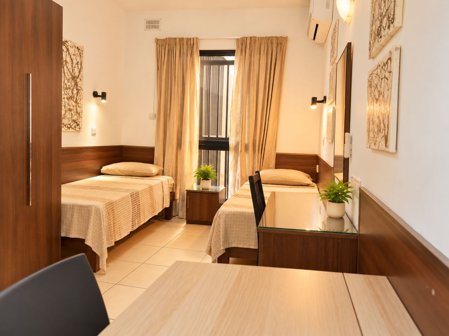 Une chambre d’hôtel avec deux lits, un bureau et une fenêtre avec des rideaux.