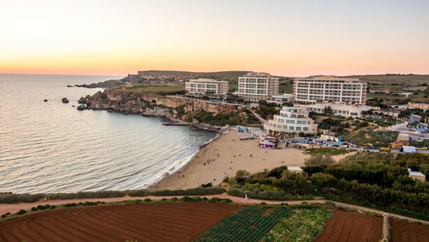 A coastal hotel with multiple buildings, a beach, and rocky cliffs. - BH2 - Seafront 3 bedroom apt. - St Paul`s Bay, Back Terrace, (San Pawl il-Bahar)