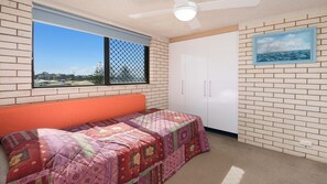 Ein Schlafzimmer mit Bett, Fenster mit Blick, Kleiderschrank und Deckenventilator.