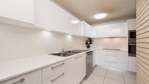 Une cuisine moderne avec des meubles blancs, des appareils en acier inoxydable et un dosseret carrelé.