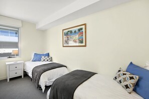 A bedroom with two beds, a nightstand, a lamp, and a framed picture on the wall.