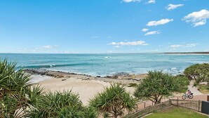 A beach with clear skies, waves, and a path with a fence and greenery. - Culverston Unit 15 Kings Beach QLD (KINGS BEACH)