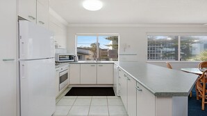 A modern kitchen with white cabinets, a built-in microwave, and a large window offering a view of the city.