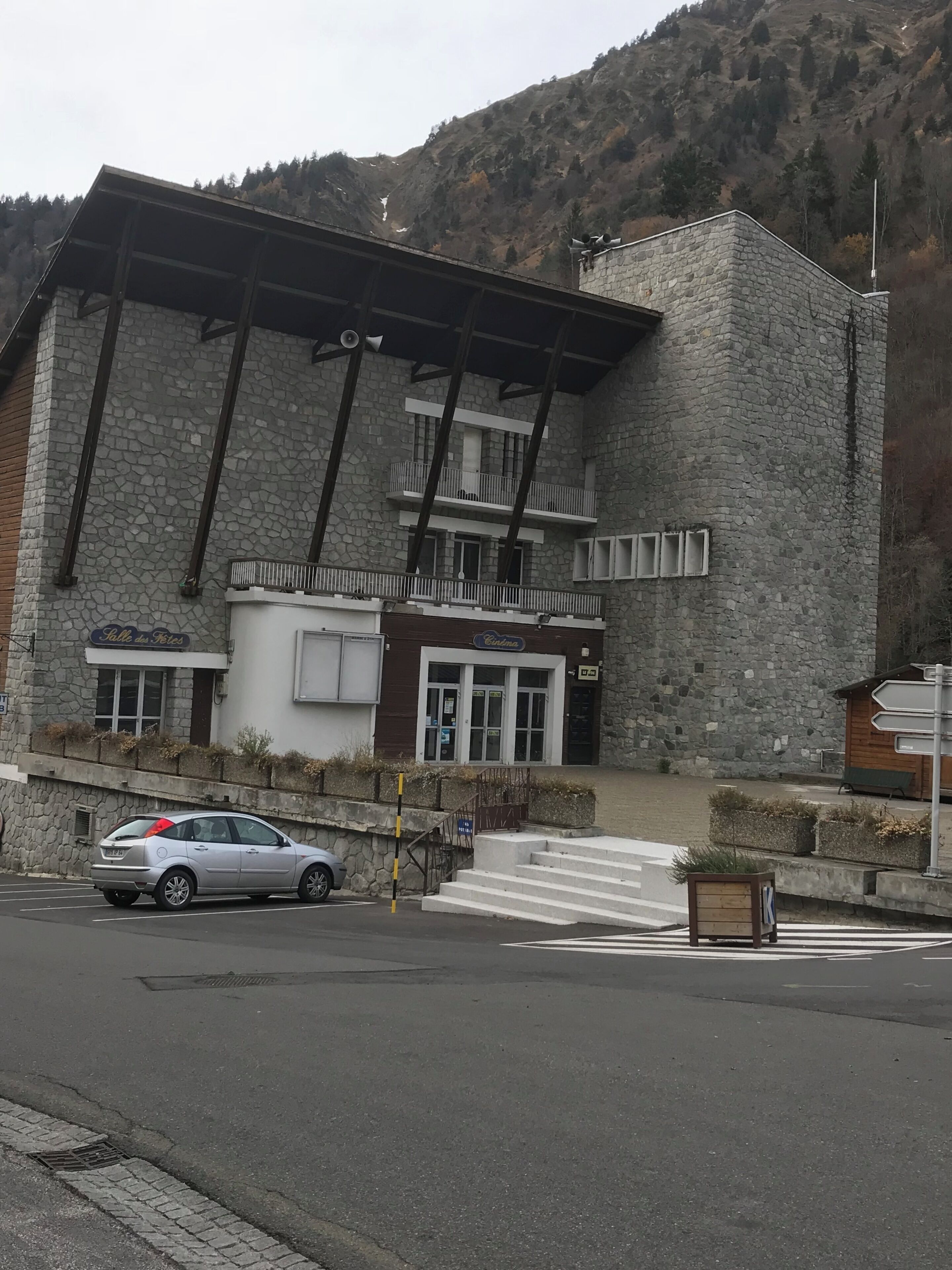 A stone building with a modern design, featuring a large entrance and a staircase leading to a second-floor balcony.