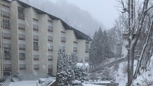Un espacio exterior cubierto de nieve con una escalera de madera que sube hacia un edificio con múltiples ventanas.
