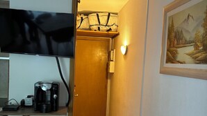 Una cocina compacta con cafetera, un refrigerador pequeño y un televisor sobre la encimera.