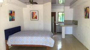 Un dormitorio con cama, ventilador de techo y vista al baño.