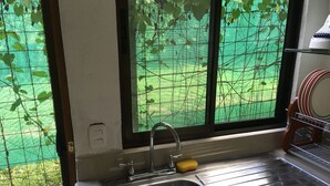 Una cocina con un lavamanos de acero inoxidable, una esponja amarilla y un escurreplatos.
