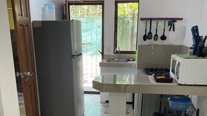 Una cocina equipada con refrigerador, microondas, pileta y un pequeño comedor.
