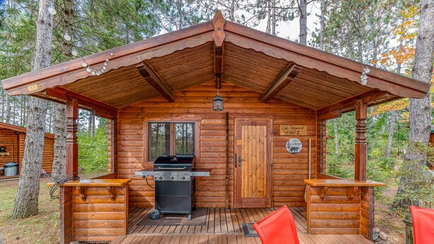 A wooden cabin with a covered deck, a grill, and a sign indicating it is number 20. - Authentic German Log Cabin in Hayward!! (Hayward)