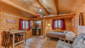 A cozy cabin interior with a wooden dining table, a bed, and a sofa. - Authentic German Log Cabin in Hayward!! (Hayward)