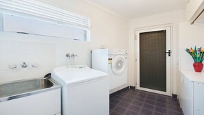 A laundry area with a washing machine, dryer, and a sink. - Moondara Unit 5, Bulcock Beach QLD (CALOUNDRA)