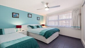 A bedroom with two beds, a ceiling fan, and a window with curtains. - Moondara Unit 5, Bulcock Beach QLD (CALOUNDRA)