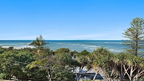 A coastal view with a beach, ocean, and dense greenery. - Moondara Unit 5, Bulcock Beach QLD (CALOUNDRA)