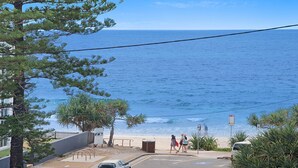 A coastal road with a beach view, a pedestrian crossing, and a parked car. - Linden Terrace Unit 2 Kings Beach QLD (CALOUNDRA)