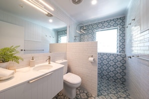 A bathroom with a white vanity, a toilet, and a shower area.