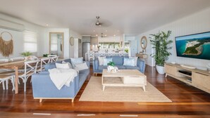 A spacious living room with a sofa set, coffee table, and a television on the right. - A Point of View - Airlie Beach (Airlie Beach)
