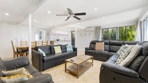 A modern living room with two sofas, a coffee table, and a ceiling fan.