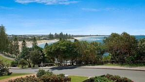 A coastal view with a beach, trees, and a road leading to a building. - Seacrest Unit 2 Moffat Beach QLD (MOFFAT BEACH)