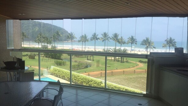 Ein Balkon mit Blick auf den Strand und Palmen.