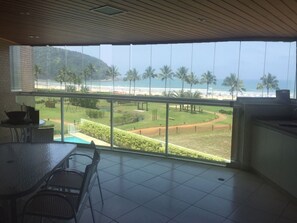 A balcony with a view of the beach and palm trees.