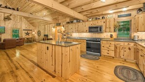 Interior de una cabaña de madera con cocina, comedor y una sala de estar acogedora.