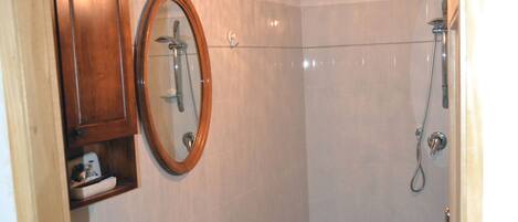Une salle de bain avec un plafond en bois, un lavabo blanc, un miroir et une douche.