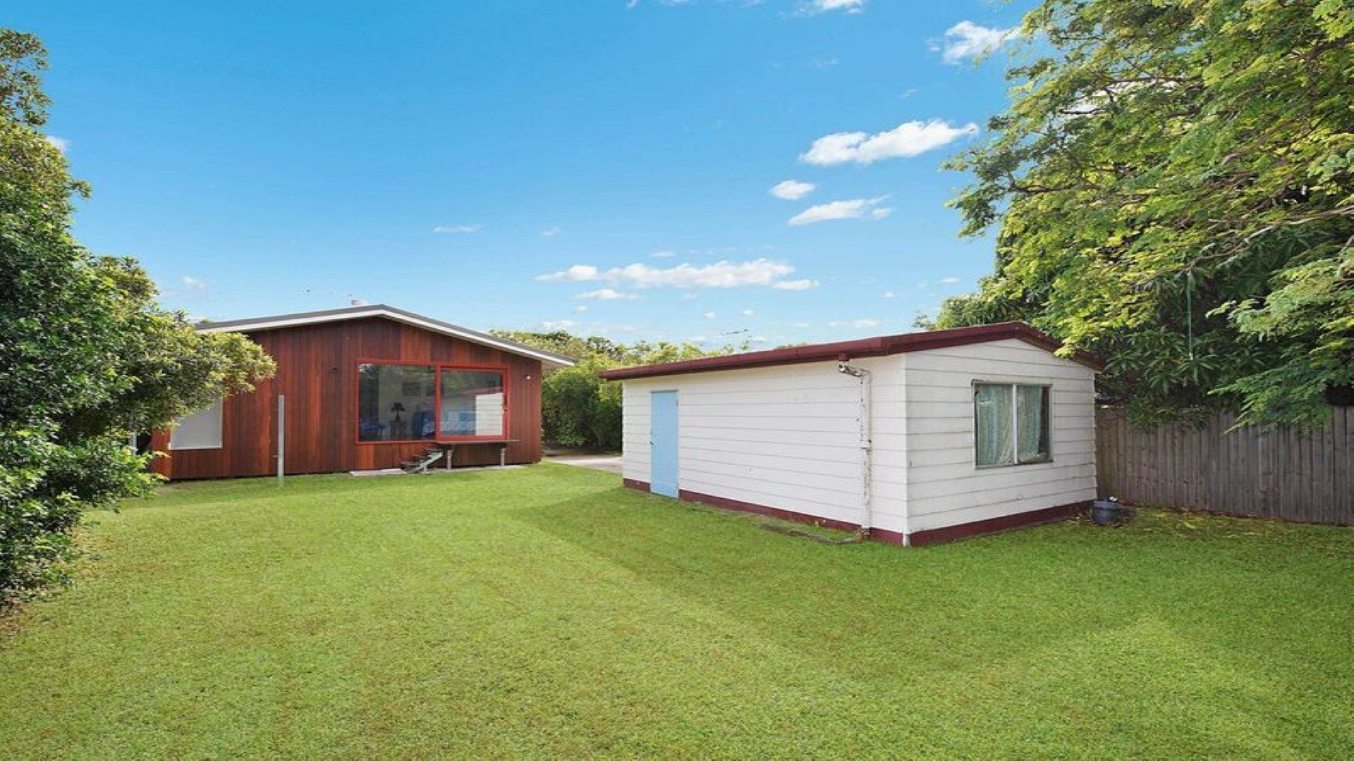 A two-story house with a red exterior and a white exterior. There is a lawn in front of the house.