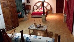 A cozy room with a bed, a wooden cabinet, a table with a basket, and a chair with a patterned cushion. - LA ALMORZARA BALCONY (Priego de Córdoba)