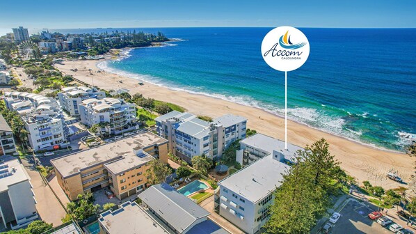 A coastal hotel with multiple buildings, a beach, and a clear view of the ocean.