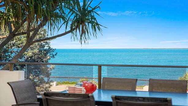 A terrace with a table and chairs overlooking a clear blue sea.