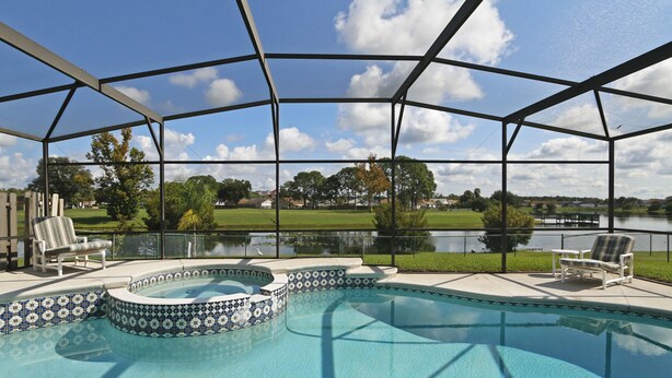 A swimming pool with a covered area, surrounded by chairs, and a view of a lake and park. - Waterview ,Private Pool, Family Friendly, Spacious and Relaxing (Kissimmee)