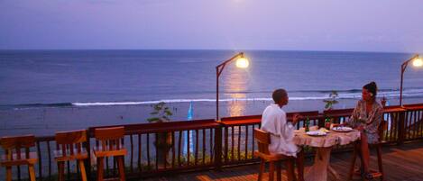 A wooden deck with a table and chairs overlooking the ocean.