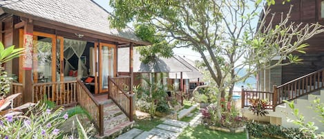 A wooden house with a tiled roof, a porch with a wooden railing, and a stone pathway leading to the entrance.