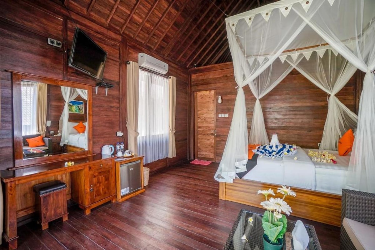 Een houten kamer met een bed, een bureau, een televisie en een raam.
