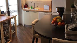 A modern kitchen with white cabinets, a wooden dining table, and a fruit bowl. - Fabulous 200sqm bright, new apartment walking distance to Duomo and city centre (Firenze)