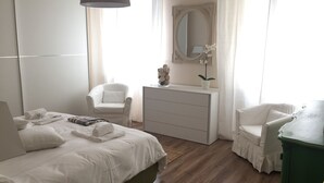 A bedroom with a bed, two chairs, a dresser, and a mirror. - Fabulous 200sqm bright, new apartment walking distance to Duomo and city centre (Firenze)